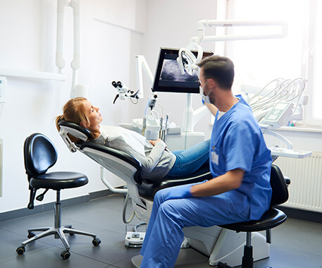 dentist speaking with woman sitting in a dental chair