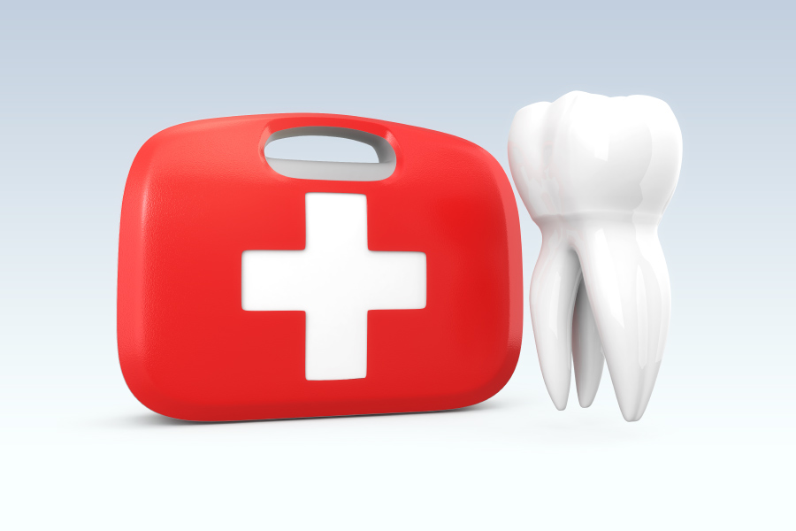 A white tooth floats next to a red and white emergency first aid kit against a gray background