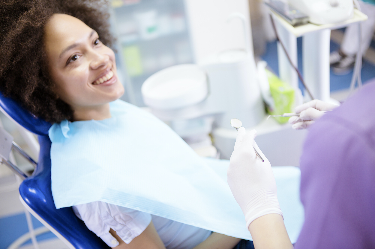 Black woman smiles while sitting in a dental chair at the dentist