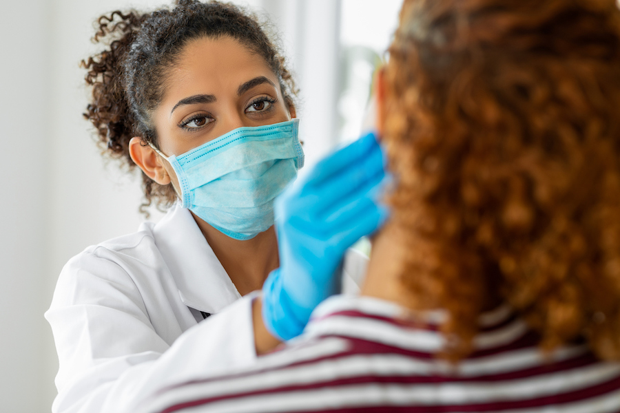 oral cancer screening, dental professional providing oral cancer screening while wearing surgical gloves and mask