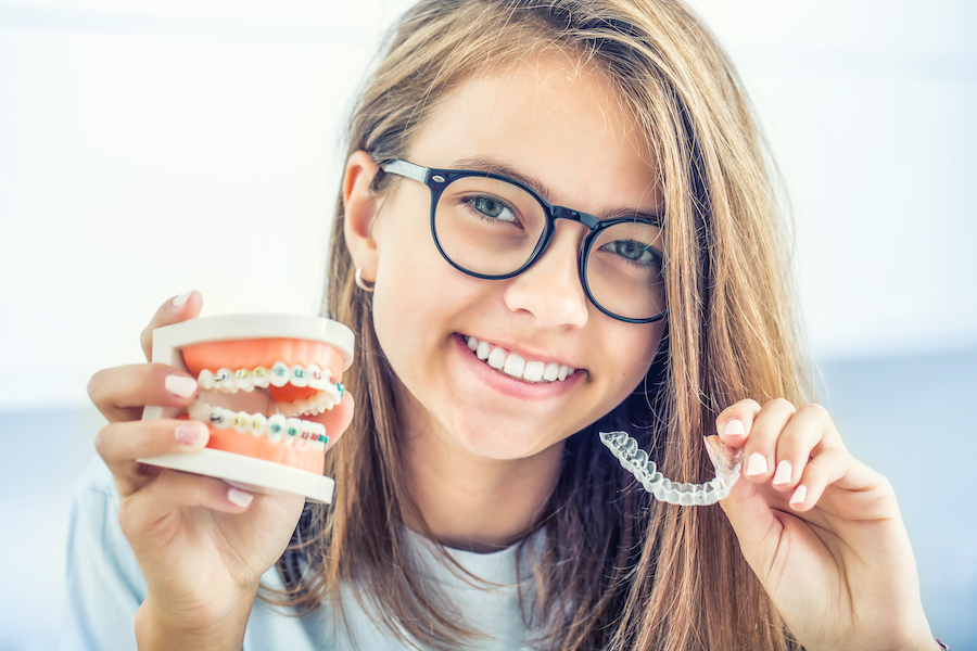 Orthodontics in Germantown MD, Dental invisible braces or silicone trainer in the hands of a young smiling girl. Orthodontic concept - Invisalign.
